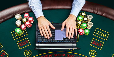 Ein Spieler am Casinotisch vor einem Laptop.