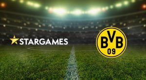 Vertreter von StarGames und Borussia Dortmund präsentieren den Sponsoring-Deal im Signal Iduna Park, mit einem Banner des StarGames-Logos im Hintergrund.