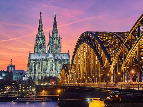 Der Kölner Dom in der Dämmerung, im Vordergrund die Kölner Brücke.